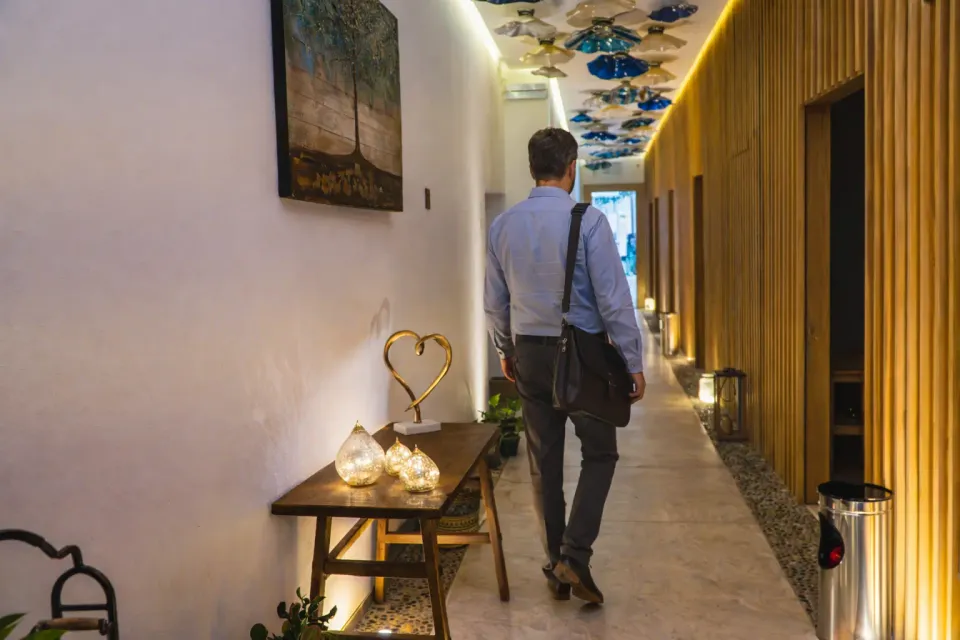 a man walking down a hallway with a table and chairs